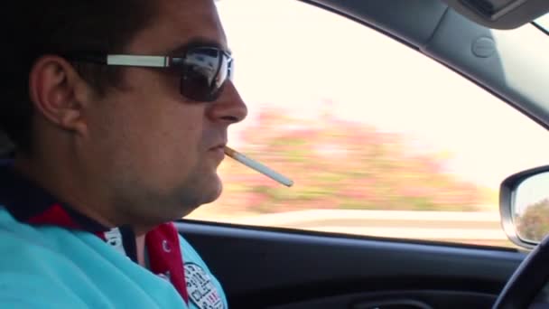 Το πρόγραμμα οδήγησης καπνίζει ένα τσιγάρο στο τιμόνι — Αρχείο Βίντεο