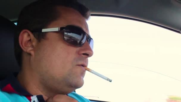 El conductor fuma un cigarrillo al volante — Vídeo de stock