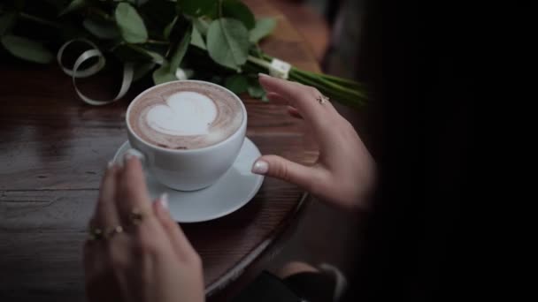 Vrouw die cappuccino drinkt met een hart — Stockvideo