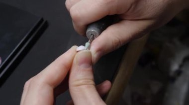 Teknisyen laboratuvarda bir diş kesiyor.