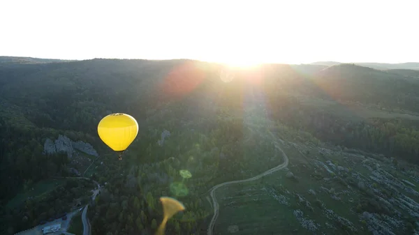 Ένα μπαλόνι πετάει πάνω από τα βουνά στην ανατολή του ηλίου — Φωτογραφία Αρχείου