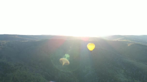 Ein Ballon fliegt im Sonnenaufgang über die Berge — Stockvideo