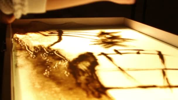 Close-up menina pintar uma ilustração com areia na mesa de luz — Vídeo de Stock
