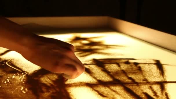 Gros plan fille peindre une illustration avec du sable sur la table lumineuse par doigt — Video