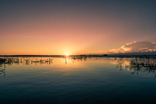 Huzurlu bir göl üzerinde renkli günbatımı
