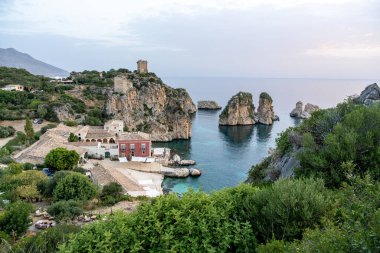 Sicilya 'da deniz yığınları, turkuaz su ve kayalık kıyı şeridi olan Scopello Körfezi manzarası