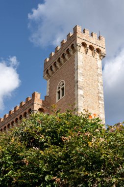 Siperleri ve dramatik bulutları olan tarihi tuğla kulesinin alçak açılı görüntüsü