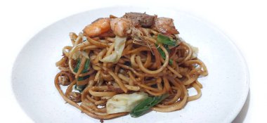 Mie Goreng or Stir Fried Noodles with Shrimp, Meatballs, Sausage and Vegetables. Traditional Indonesian Cooking. Food Photography Presentation. Isolated on White Background