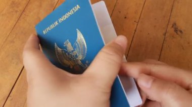 Bekasi, Batı Java, Endonezya - 24 Aralık 2025. Eller ahşap masada Endonezya pasaportu gösteriyor.