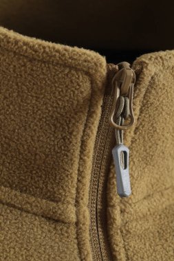 Gri arkaplanda kahverengi bir fermuarın dikey yakın çekimi