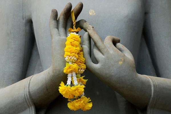 Mani di Budhda statua con ghirlanda di fiori Foto Stock