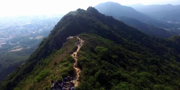 Jeunes randonneurs au sommet d'une montagne assis sur la falaise escarpée profitant d'une vue sur la vallée — Video