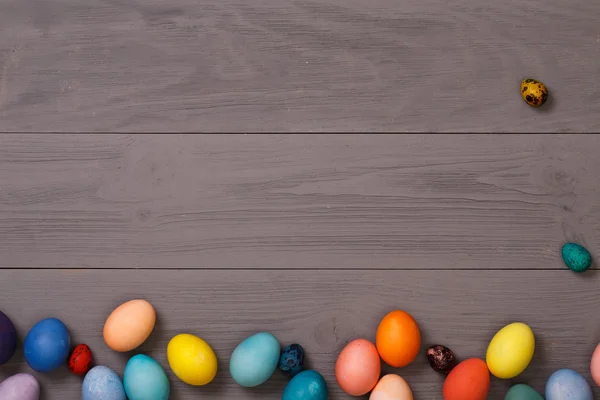 Lugar de trabajo de madera con huevos de colores — Foto de Stock