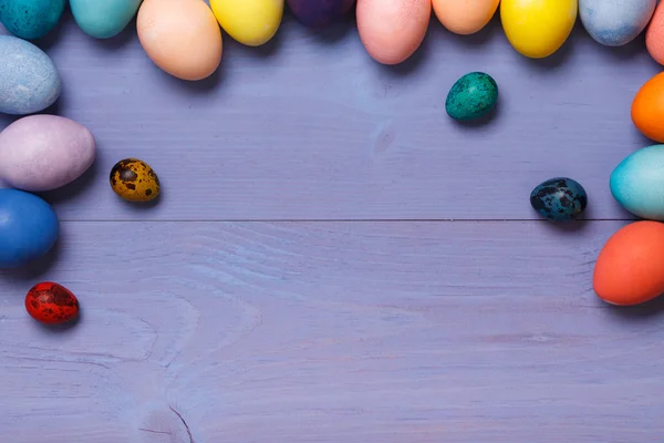 Local de trabalho de madeira com ovos coloridos — Fotografia de Stock