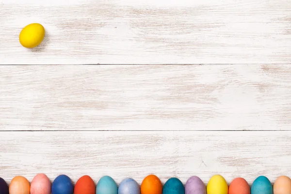 Lugar de trabajo de madera con huevos de colores — Foto de Stock