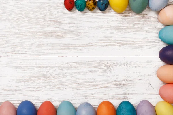 Local de trabalho de madeira com ovos coloridos — Fotografia de Stock