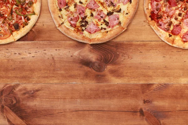 Três pizzas saborosas na mesa — Fotografia de Stock