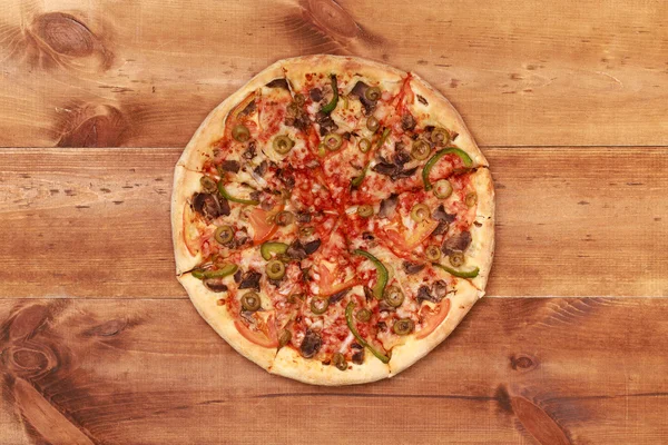 Deliciosa pizza na mesa de madeira — Fotografia de Stock