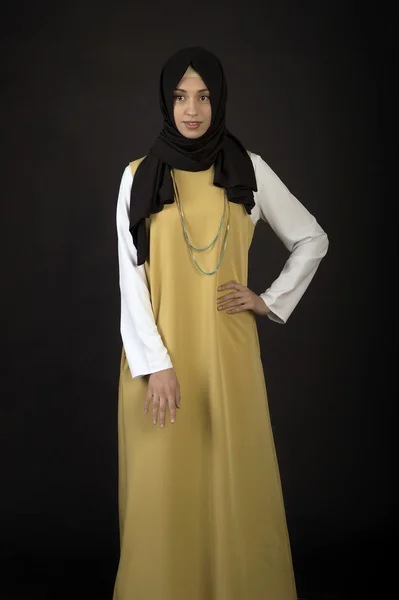 Foto einer jungen orientalischen Frau in moderner Kleidung mit einem Moslem in einem Schal auf dunklem Hintergrund — Stockfoto