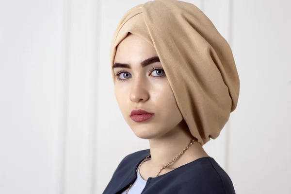 Studio ritratto di ragazza orientale con un bel viso con turbante copricapo sul classico sfondo chiaro — Foto Stock