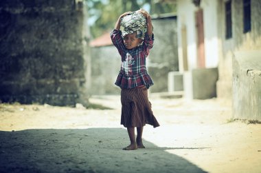 Fotoğraf Müslüman kız çıplak ayakla dervne Ekim 2014 yılında Madagaskar'da filme başlarına Bagaj ile yürürken 