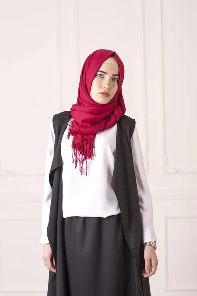 studio portrait of young woman Caucasian appearance in the modern Muslim clothes and a scarf on her head on a light classical background