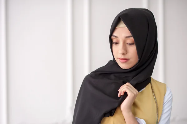 Potret studio seorang wanita muda yang cantik dari penampilan Timur Tengah dalam pakaian wanita Muslim modern dan syal di kepalanya, pada latar belakang klasik terang — Stok Foto