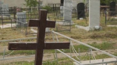 Eski Rus boş mezarlığının arka planındaki ortodoks kahverengi ahşap haçı kapatın. Kasvetli, Hristiyan, mezarlık, gömme yeri, insan yok, mezar, mezar taşı, taş anıtlar. Bulutlu bir gün.
