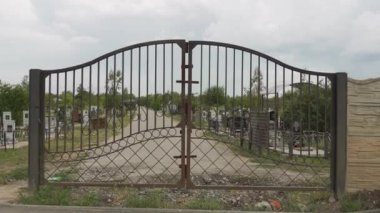 Mezar taşları ve mezarları olan eski paslı kapıları Ortodoks Rus mezarlığının arka planında görmek. Mezarlığın üzerindeki kasvetli bulutlu gökyüzü. İnsanların gömüldüğü yer. Giriş. Yeşil Park.
