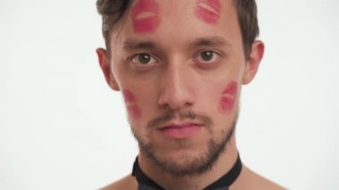 Kısa kahverengi saçlı, sakallı, yüzünde kırmızı ruj izleri olan beyaz tenli yakışıklı, seksi bir adam. Kadınlar için komik romantik bir konsept.