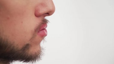 Koyu kahverengi sakallı, bıyıklı, büyük burunlu, beyaz arka planda kadın rujuyla boyanmış pembe dudaklı yalnız bir adam görüntüsü. Erkeklerdeki kadın niteliklerinin homoseksüelliğin dışavurumu