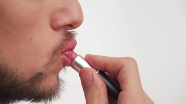 Koyu kahverengi sakallı, genç, seksi Avrupalı esmer adam. Bıyık, pembe ruj, boya dudaklar, makyaj. Ağız tarafı görünümü yakın. Uzayı kopyala LGBT 'nin haklarını koruma kavramı.