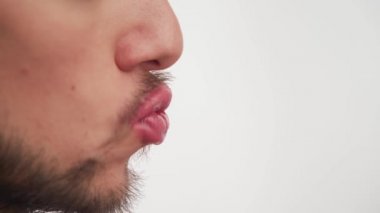 Makyajlı beyaz travesti ağzının yan görüntüsü. Kahverengi sakallı, bıyıklı, dudaklarına şaplak atan, beyaz arka planda izole edilmiş pembe ruj süren moda bir erkek. Boşluğu kopyala.