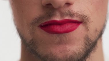 Bekar, genç, efemine, beyaz, esmer, sakallı, bıyıklı, dudakları kırmızı rujlu, gülümseyen adam, tekrar et. Beyaz arka planda güzel travesti bir erkeğin ağzını kapat..
