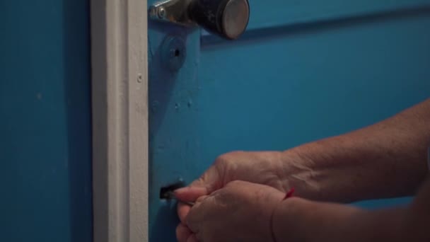 閉じるビューの認識できない高齢者の女性の手を 女性は 暗い部屋で青い木製のドアを閉じ キーを使用します 鍵を鍵穴に入れるのは難しい — ストック動画