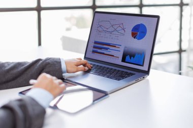 İşadamı dizüstü bilgisayarda çalışıyor ve ofiste akıllı telefon kullanıyor.