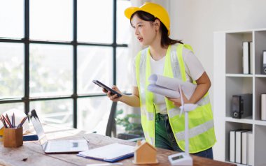 Asyalı mühendis kadın mühendis. İnşaat alanının planlarıyla evde çalışıyor..