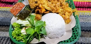 Geleneksel bir pirinç, geleneksel kızarmış kalamar, kızarmış patlıcan, salatalık dilimleri, sebzeler, ıspanak ve baharatlı sambal (sos)..