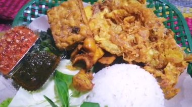 4k geleneksel pilav, geleneksel kızarmış kalamar, kızarmış patlıcan, salatalık dilimleri, sebzeler, ıspanak ve baharatlı sambal (sos) biberinden yapılır..