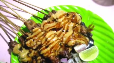 Keçi satay, soya sosu, limon dilimleri, arpacık soğanı dilimleri, acı biber dilimleri, doğranmış domates ve çiğ fasulye filizi ile servis edilen ızgara keçi etinden yapılan bir yemektir.