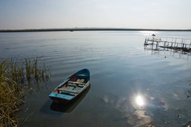 Don nehrinin kıyısındaki suda tahta kayık. Balıkçıların tekneleri suda görülebilir. Güneşli ve bulutsuz bir gün.