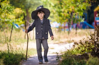 Sivri şapkalı çocuk dışarıda sihirli değnekle oynuyor. Küçük büyücü. Cadılar Bayramı konsepti.