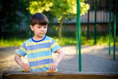Sevimli küçük çocuk, yazın, gün batımında küçük oyuncak arabalarla oynuyor..