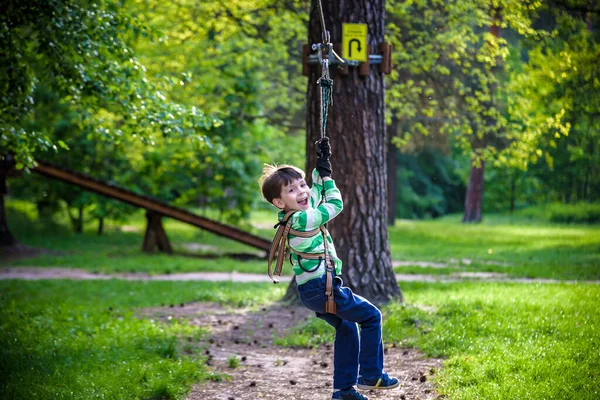 smiling boy rides a zip line. happy child on the zip line. The kid passes the rope obstacle course.