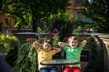 İki küçük çocuk otel restoranında ya da şehir kafesinde sağlıklı bir kahvaltı için masada bekliyor. Çocuk rahat sandalyeye oturur, rahatlar, tatilinin tadını çıkarır. Çocuk konseptiyle yaz tatili.