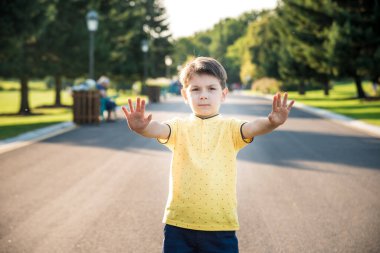 Mutlu çocuk yolda dikilirken elinde dur işareti yapıyor..