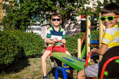 İki küçük kardeş yaz bahçesinde ya da oyun bahçesinde salıncak dengeleyicisiyle oynuyorlar. Arkadaşlık kavramı.