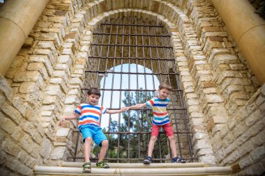 Genç kardeşler antik bir taş kapının yanında. Çocuklar gülümsüyor ve mutlu bir yaz tatili geçiriyorlar..