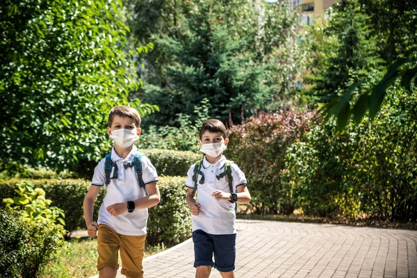 Happy schoolchildren with face masks run from the joy of returning to school during the Covid-19 quarantine.