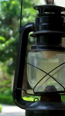 Duvara asılmış, soluk duvara karşı yumuşak gün ışığında sarmaşık yapraklarıyla kaplı klasik fener, doğanın bahçe atmosferinde kırsal bir dekorla harmanlandığını gösteriyor. Yüksek kalite 4k 